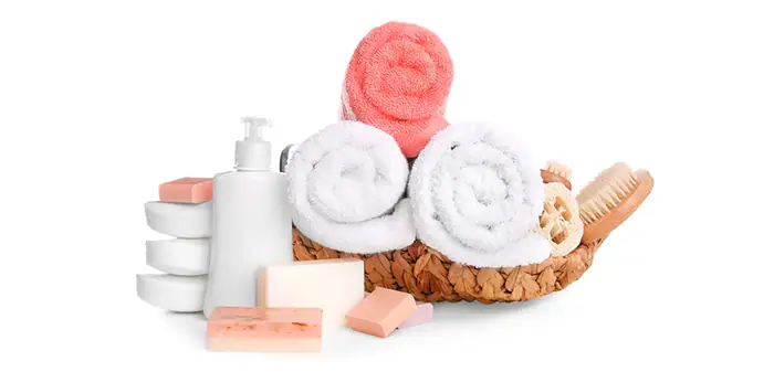 Towels, soap, and bath accessories arranged in a wicker basket for coastal bathroom decor.