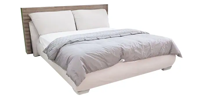 Soft gray comforter on a cozy, modern bed with white pillows and a wooden headboard in a coastal-themed bedroom.