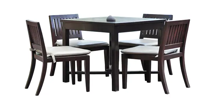 Dark wood dining table with four matching chairs and white cushions for coastal-themed home decor.