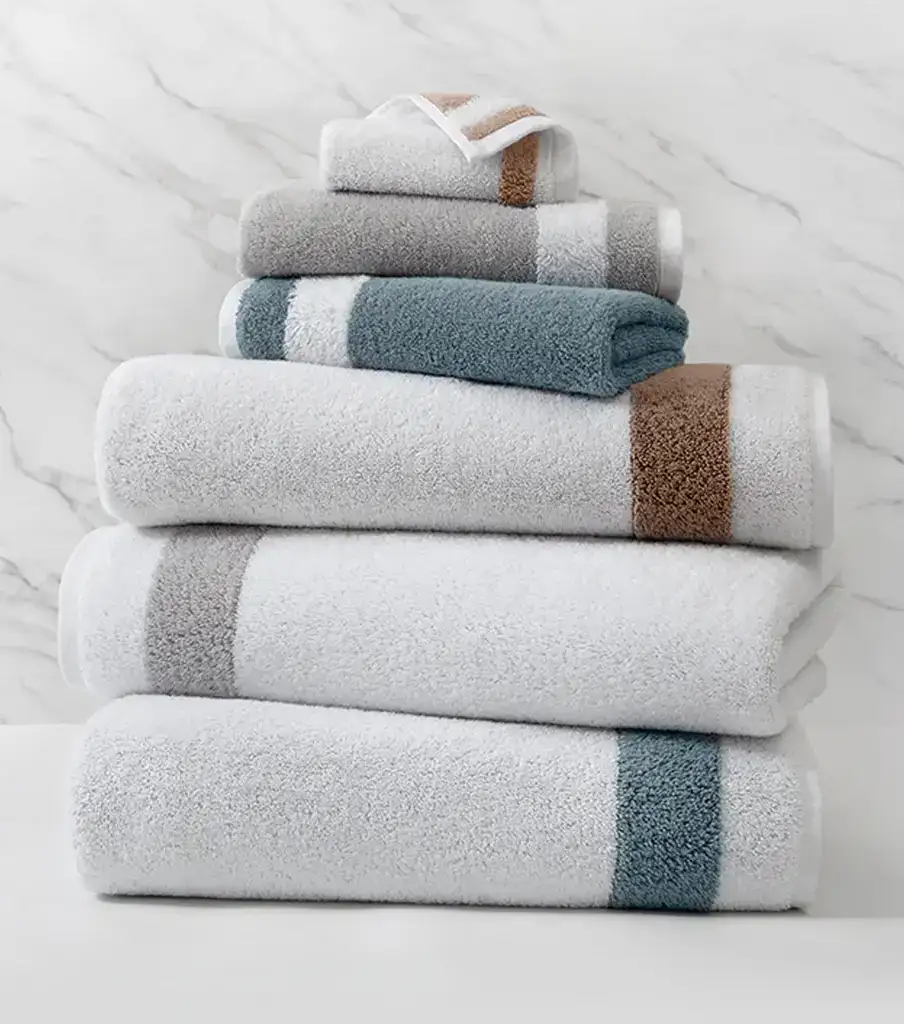 Luxury hotel towels stacked on marble surface Coastal furnishings for beach house bathroom beach towels Ocean-inspired towel set for coastal home decor.